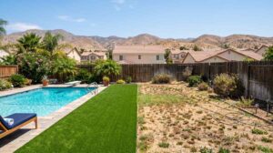Split view of lush artificial turf next to a pool and dry natural grass in an Inland Empire backyard